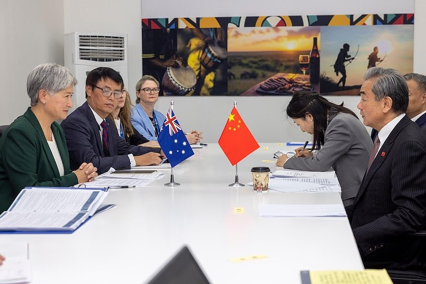 Officials wearing suits seated on a table facing each other