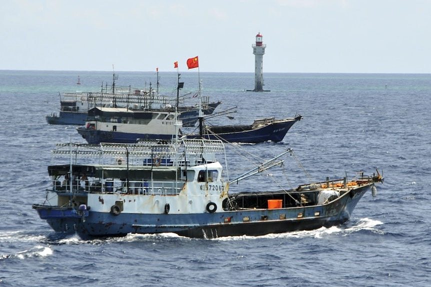 Chinese fishing vessels navigate past a beacon in the Zhubi Reef