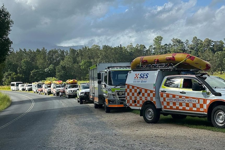 A long row of SES branded trucks with kayaks attached to the rooves.