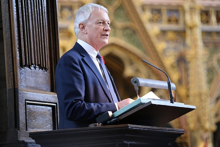 A man wearing a suit speaks at a lectern