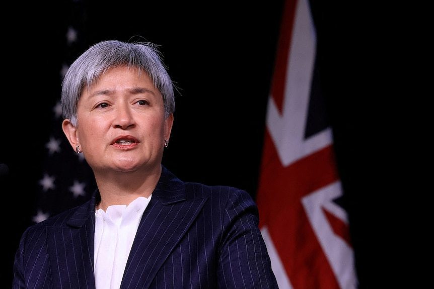 Penny Wong speaks while standing in front of US and Australian flags