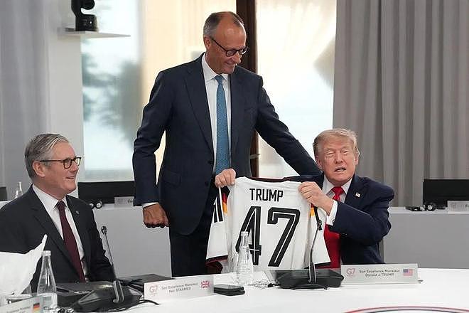 默茨送特朗普德国队球衣作为生日礼物,上面印有“Trump”字样和数字“47”,特朗普敷衍对待,第一时间未接过球衣,默茨十分尴尬 - 2