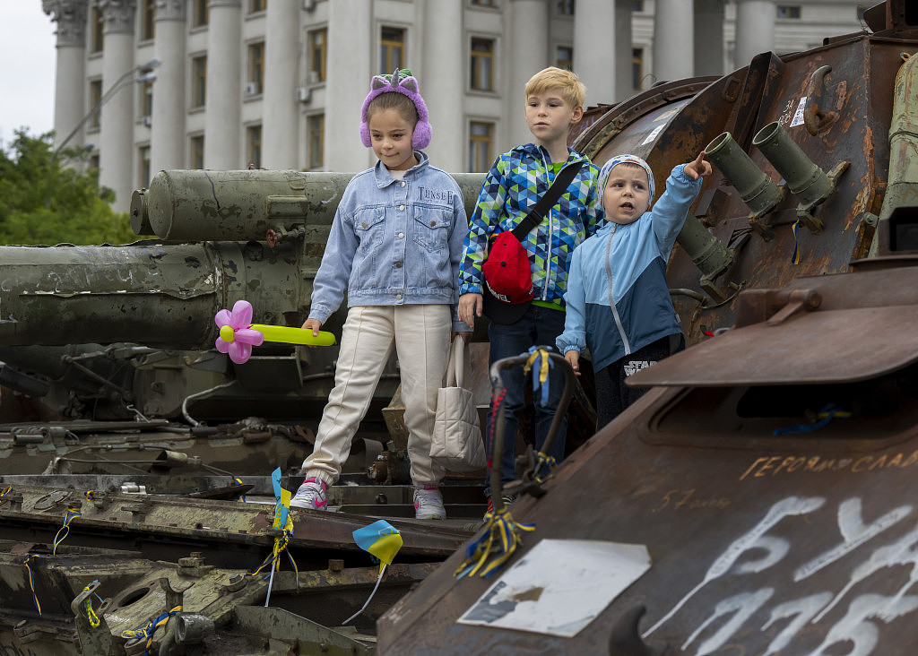 孩子們站在烏克蘭基輔聖邁克爾廣場燒毀的俄羅斯坦克上。路透