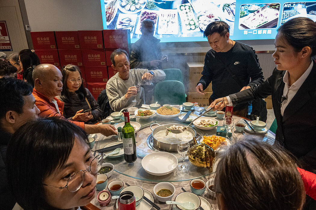 深圳，一家热闹餐馆里的香港人。深圳的一些餐厅为电话号码有香港区号852的顾客提供折扣。

